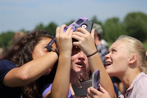 Students taking photo on iphone through solar eclipse glasses.