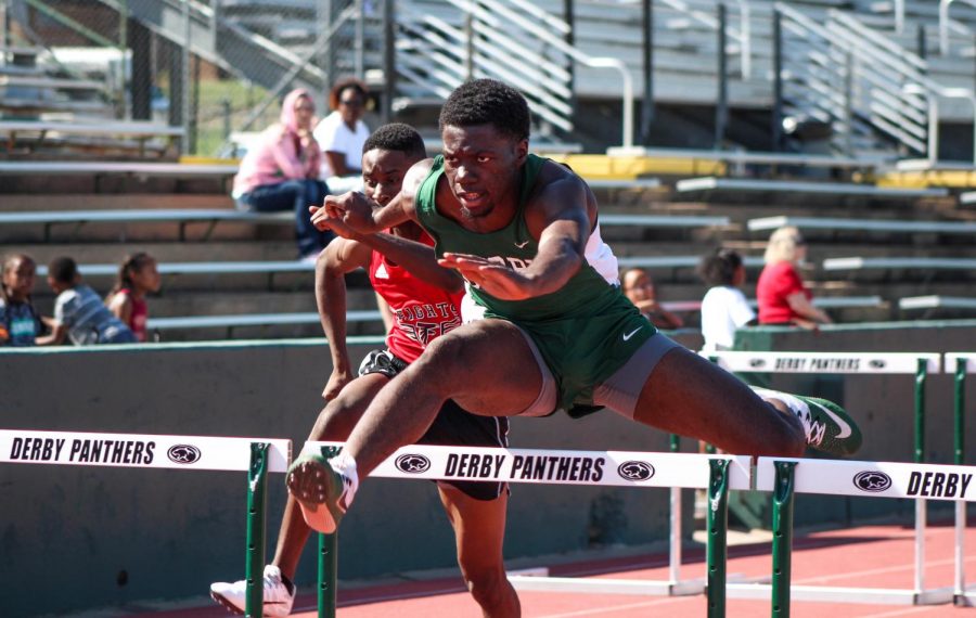 Senior Adrian Brown leaping over the hurdles as hes in the lead.