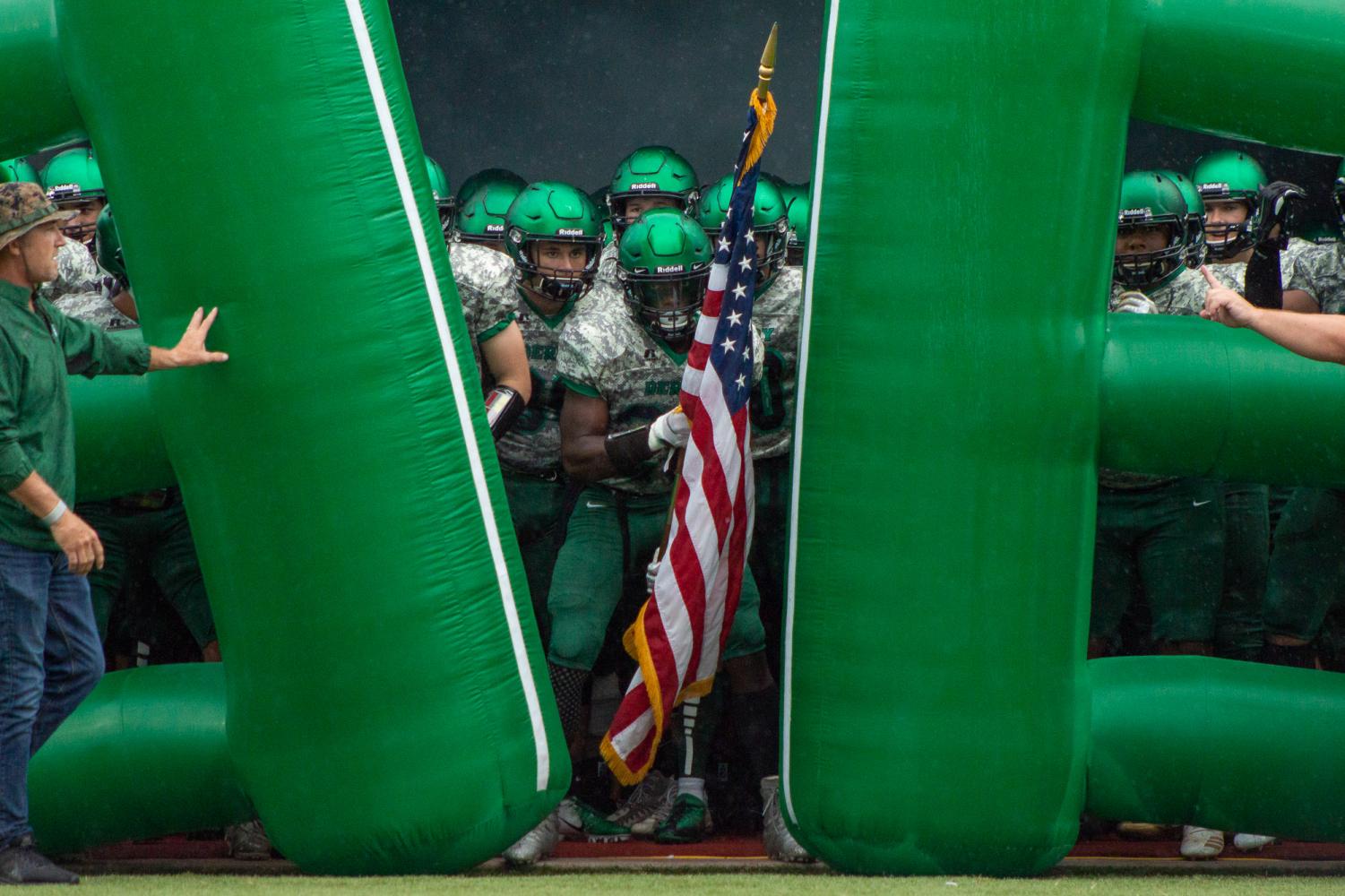 Senior Ejavion Fisher holds the American Flag as his team waits to be released out of the helmet tunnel. Photo by Regina Waugh
