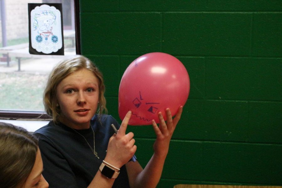 Freshman+Haleigh+Harris+pointing+the+the+face+she+made+on+her+balloon.