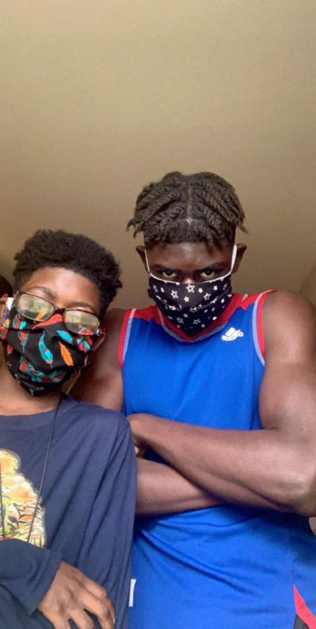 Freshman Samuel Same Ndoumbe poses with his little brother Thomas while wearing their masks.