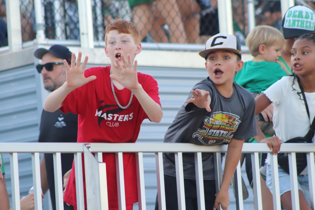 Two young boys gesture for junior football players to throw the ball to them.