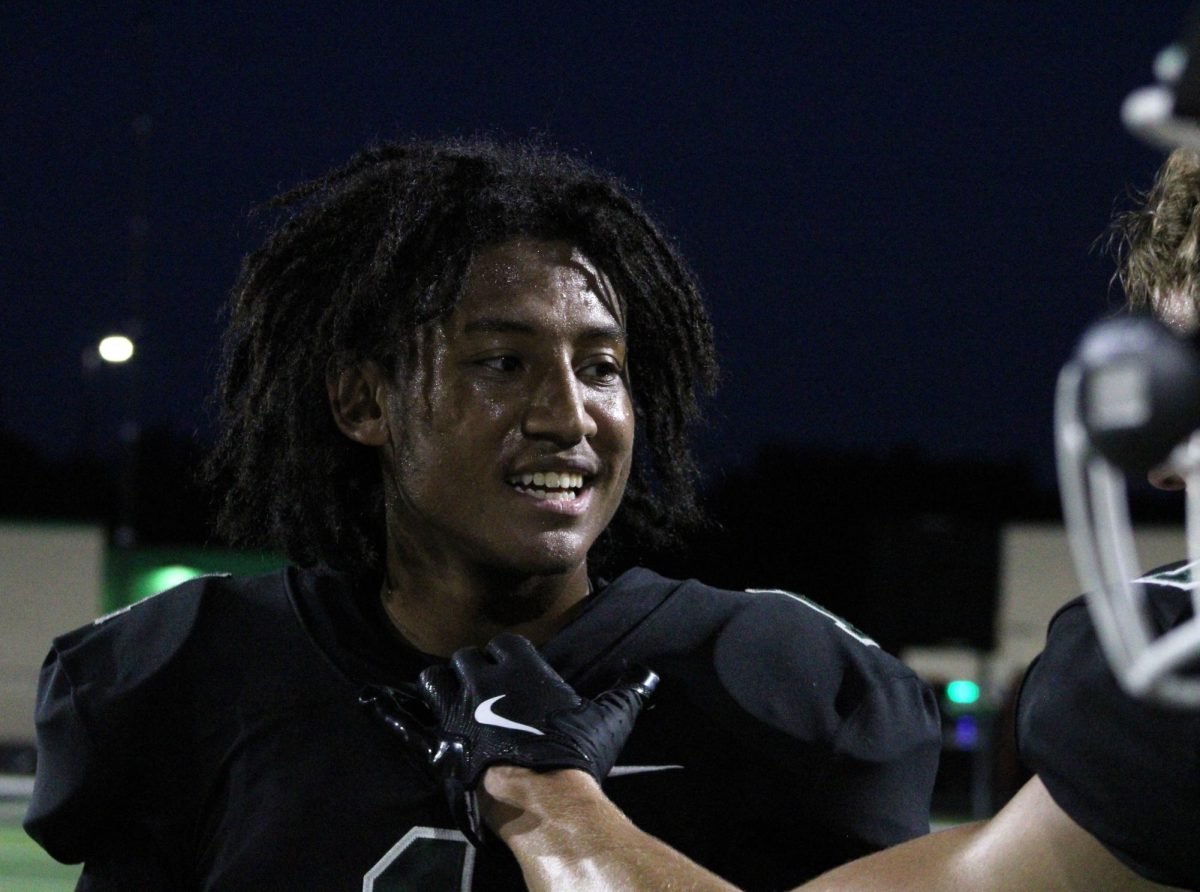 Senior Isaiah Henriques smiles at his teammate as they talk from the sidelines.