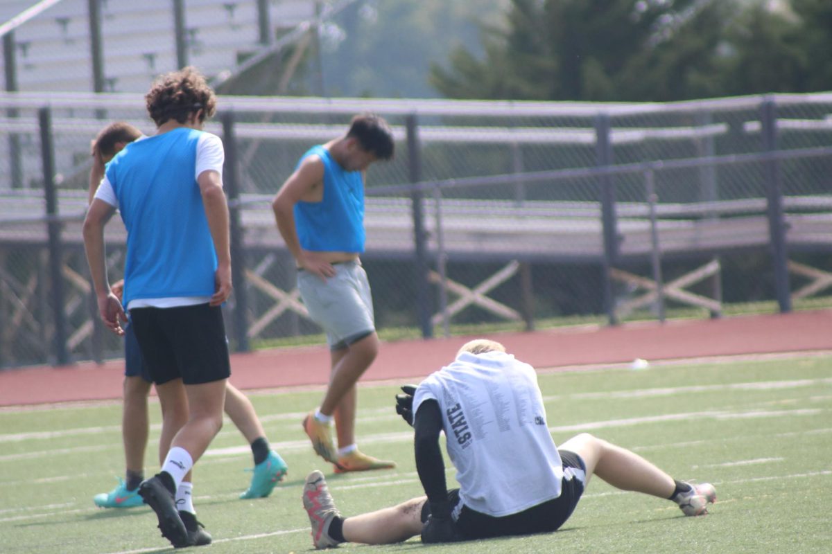 Soccer player sits on field during practice. 