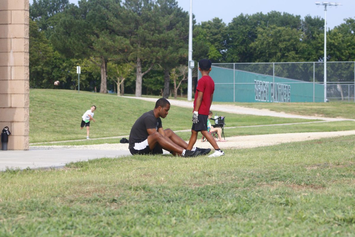 Person on sidelines ties little league players shoe. 