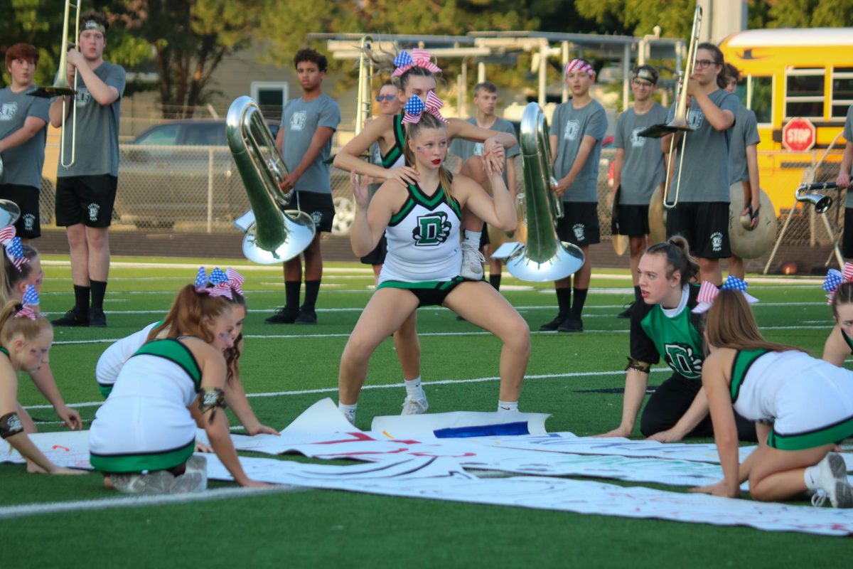 Cheerleaders getting in position to hold football sign. 