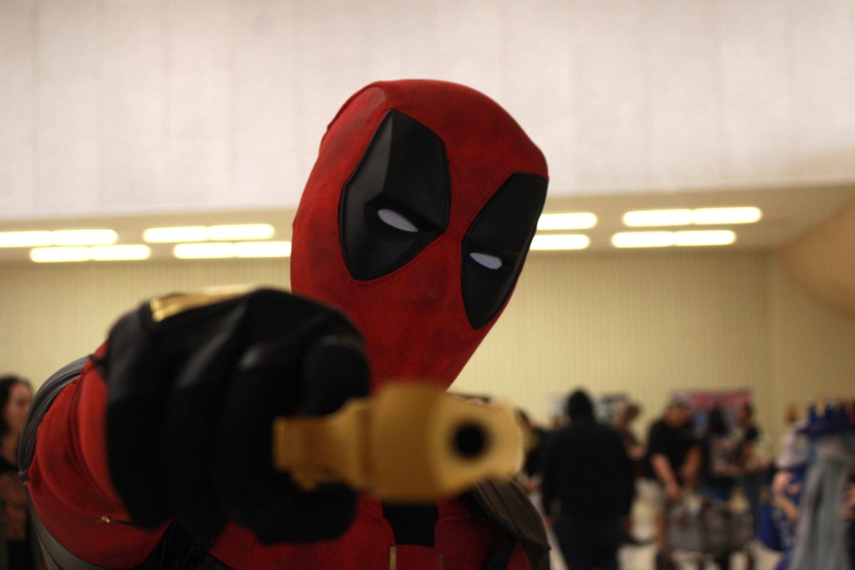 Deadpool cosplayer points prop at the camera.