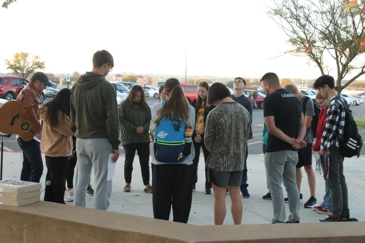 Students gather around in a circle to pray all together. 