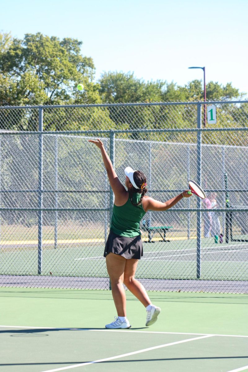 Player throws tennis ball up in the air. 