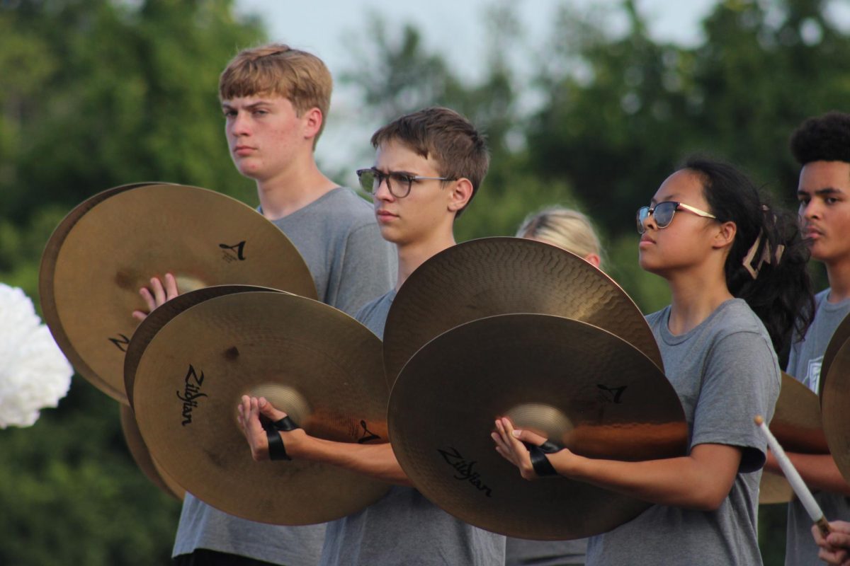 Front ensemble members play the cymbals at the tailgate 