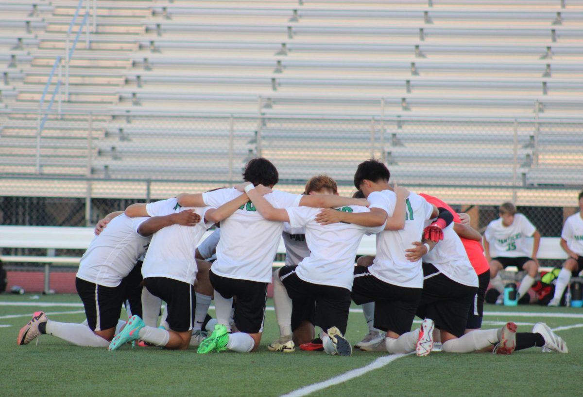 Varsity soccer players pray before kick off.