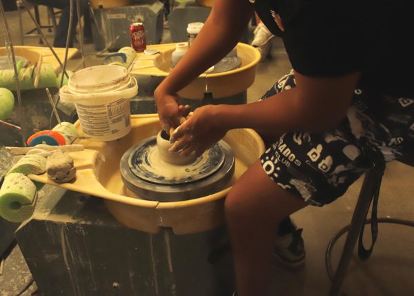 Student shapes bowl with a sponge.