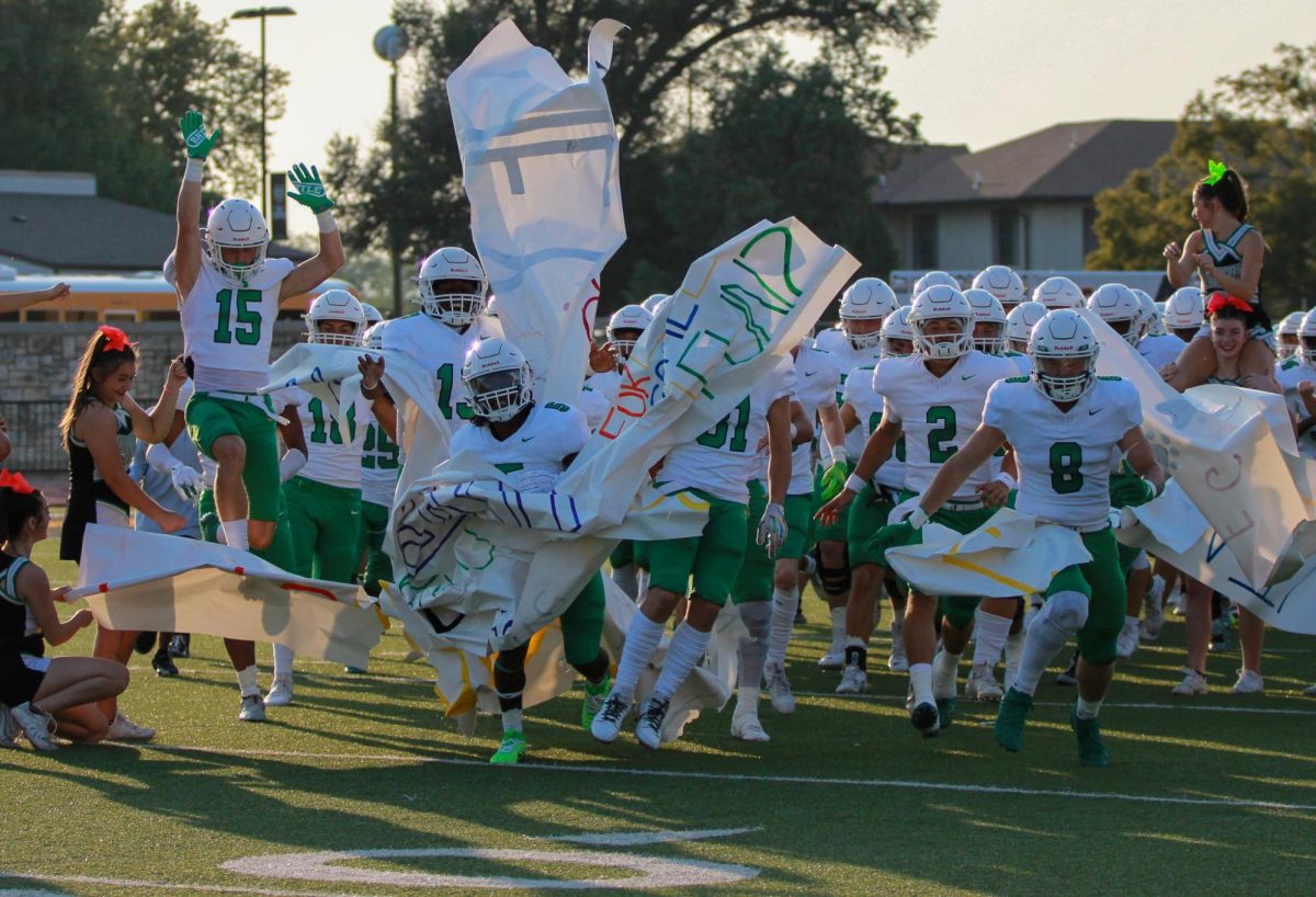 Football team runs through sign.