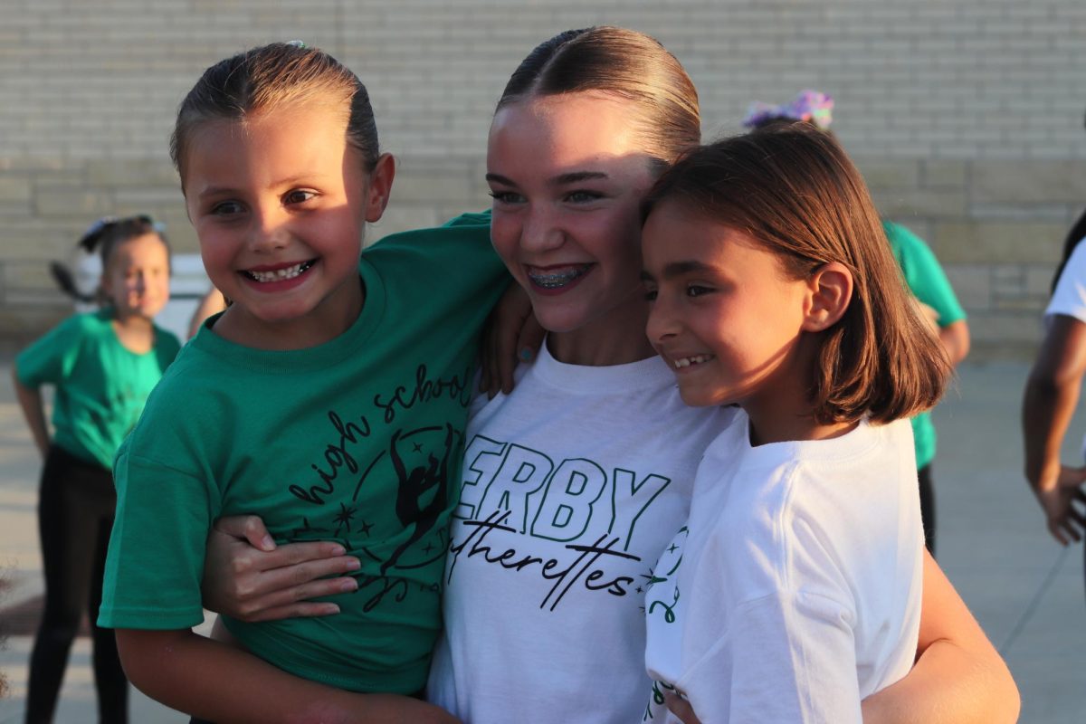 Junior Avery Burkholder poses with two kids for a picture.