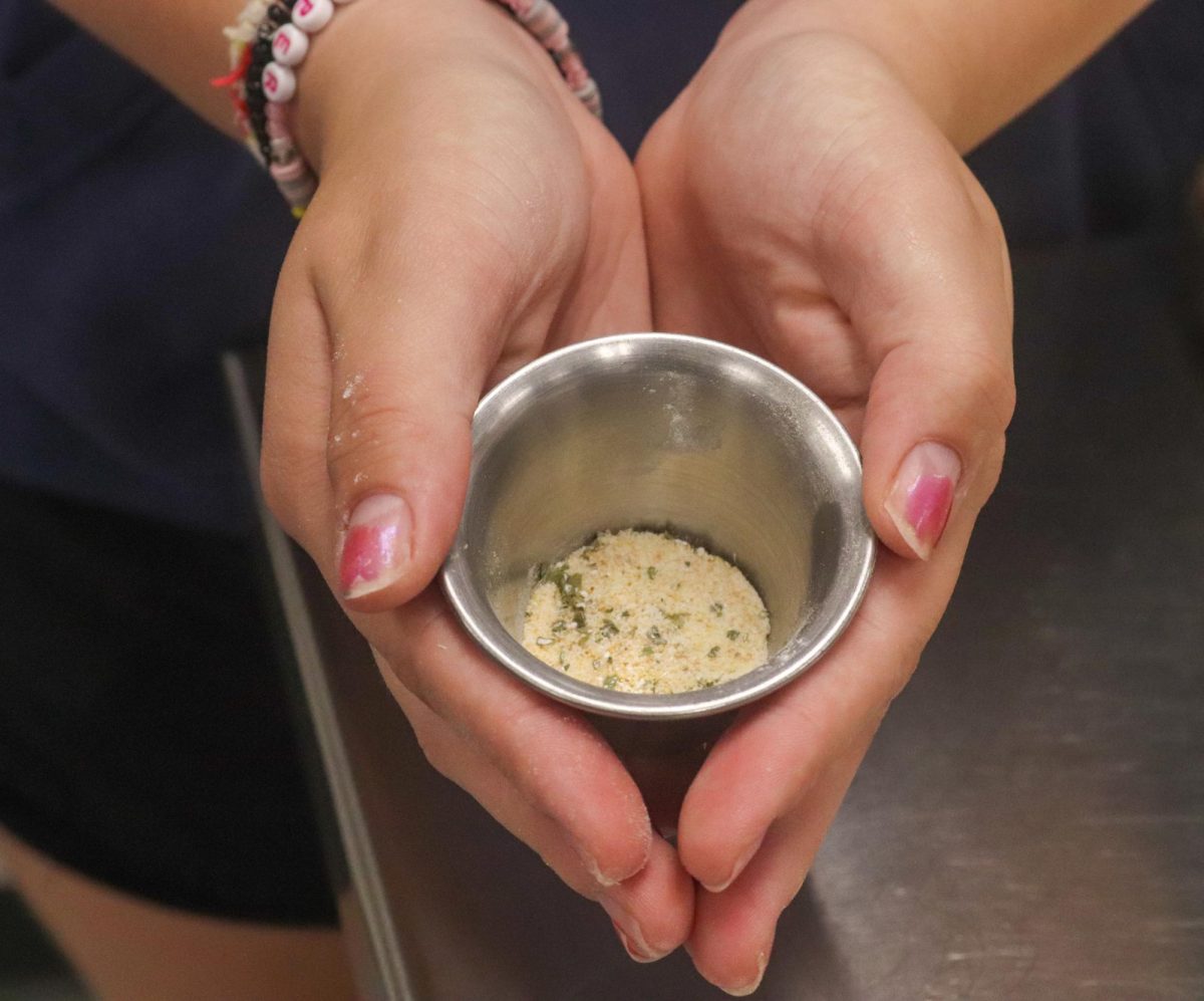 Student holds the seasonings used for the fries.