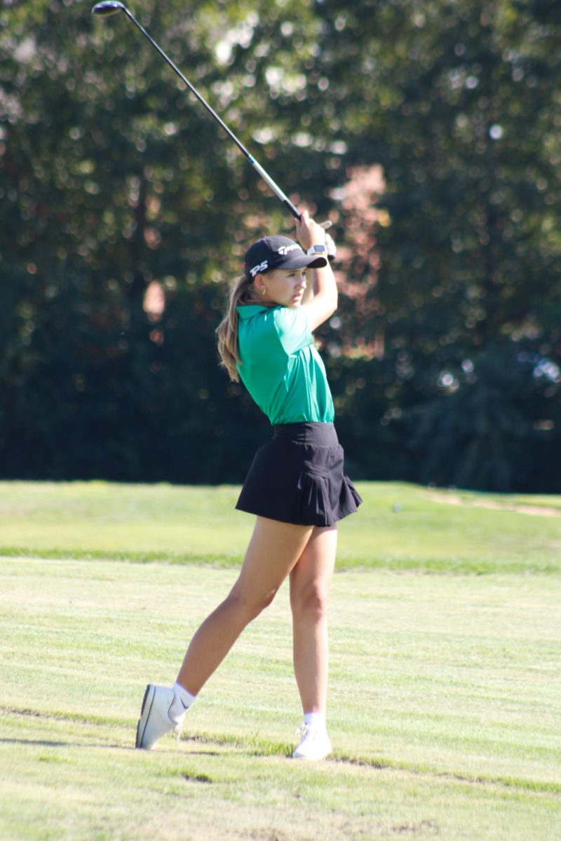 Junior Addison Oetken swings golf club from hitting the ball.