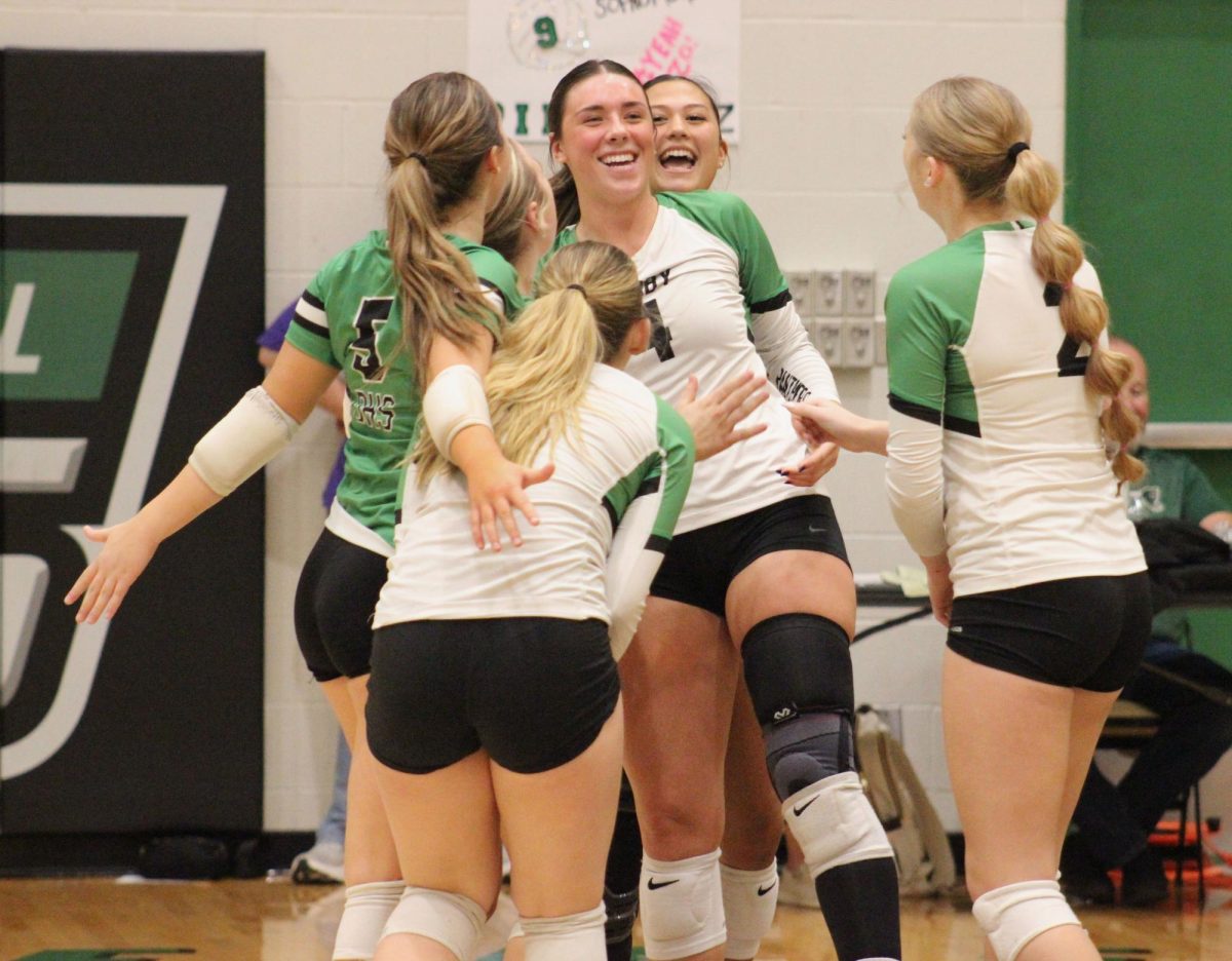 Varsity volleyball team celebrates with senior Carsen Carpenter in the center.