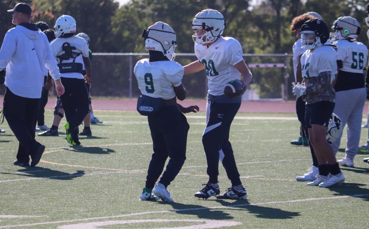 Teammates talking on the field while waiting for play.