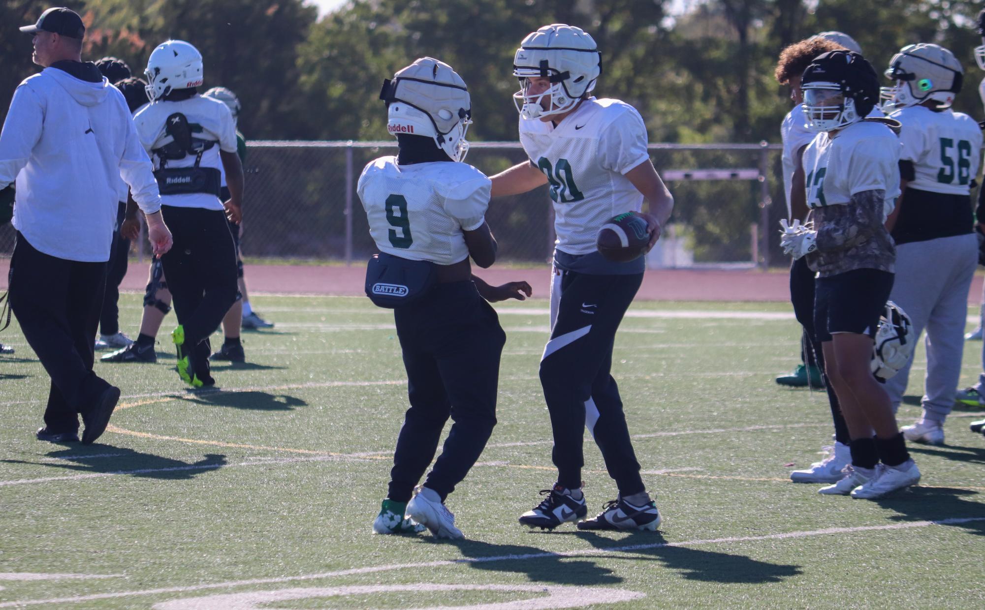 Teammates talk to one another on the field while they wait for the next play.