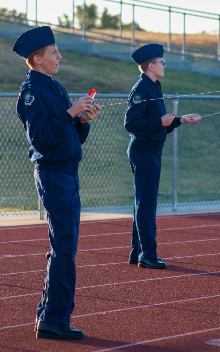 Friends work together to fly their kites. 