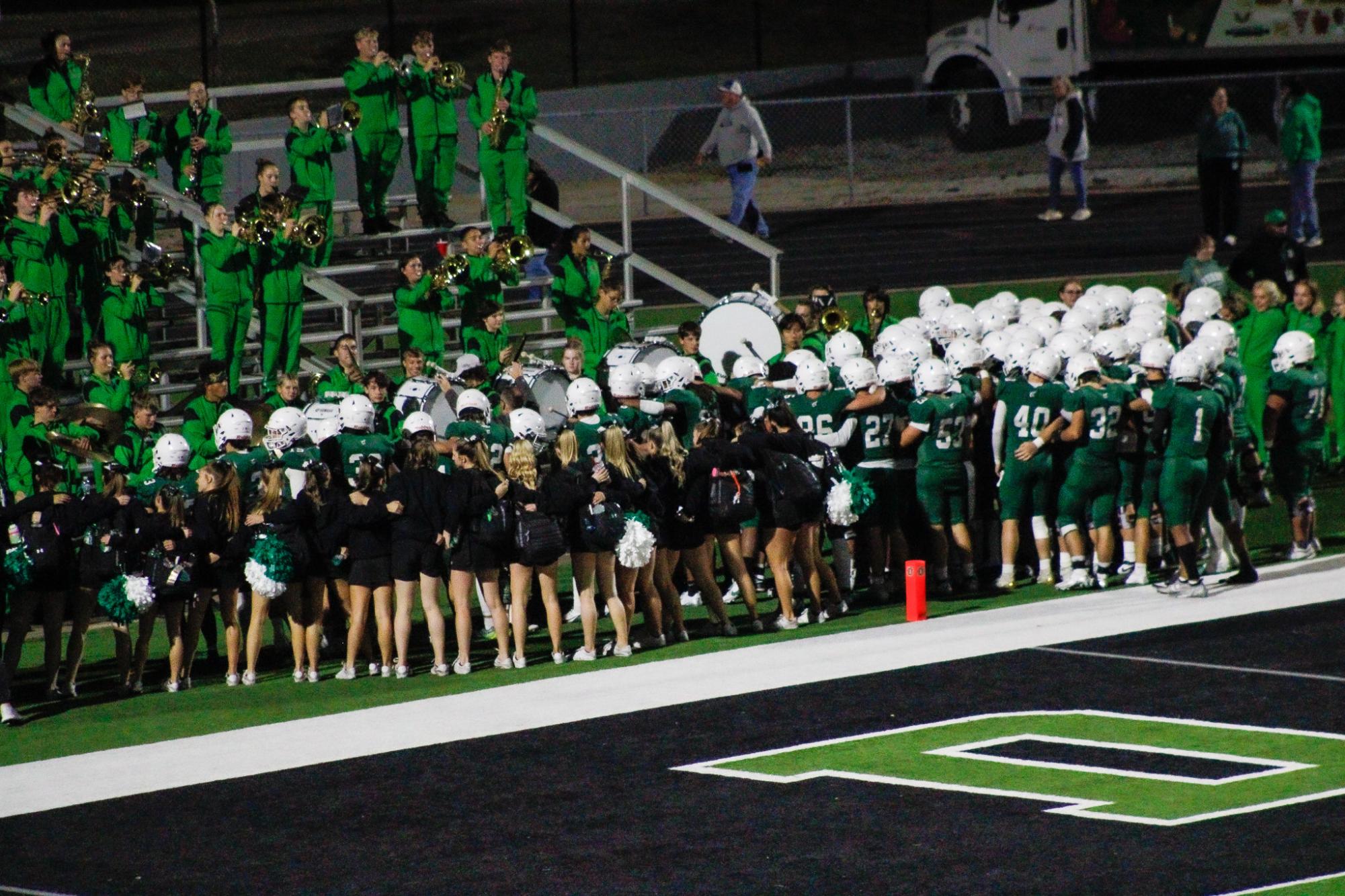 Football players, band members, cheerleaders, and pantherettes gather around for the Alma Mater.