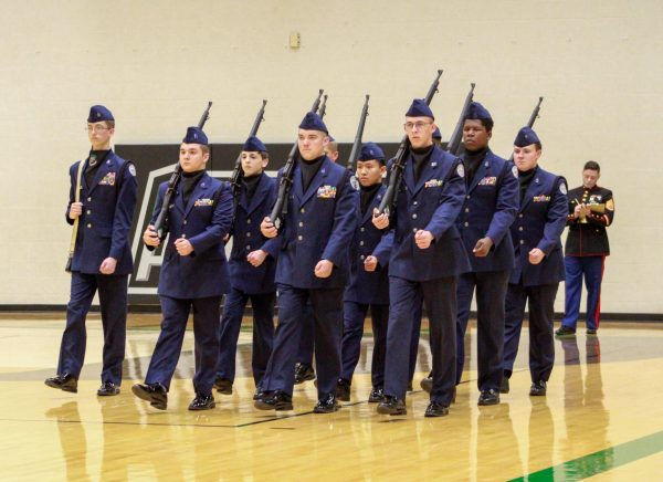 A group of AFJROTC members march forward.