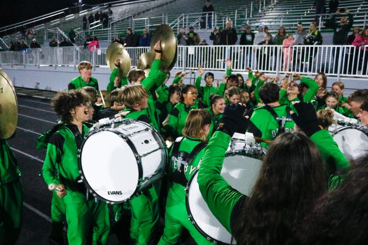 Marching band and Color guard members cheer and play at the end of the game. 