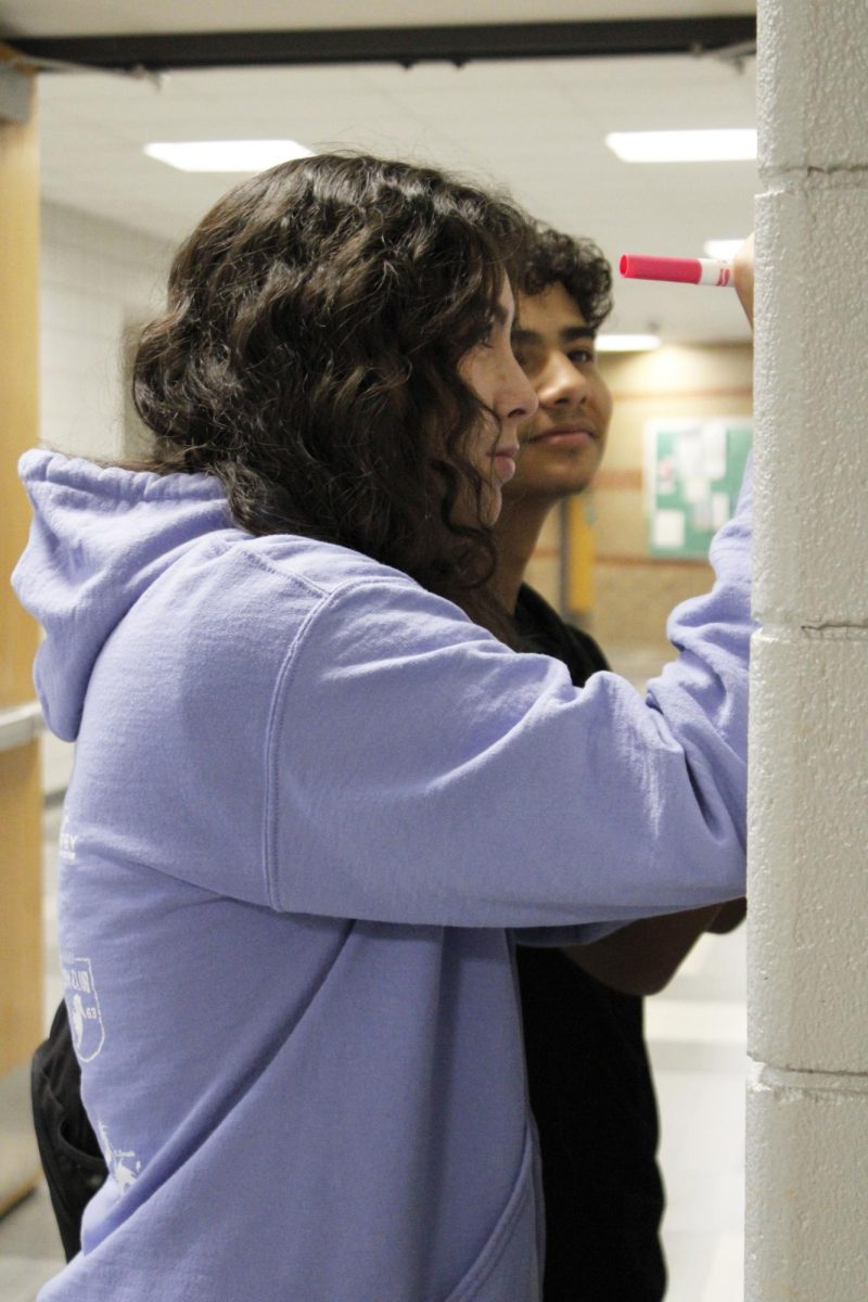 Reality 101 Peer Mentor helps student write name on name tag.