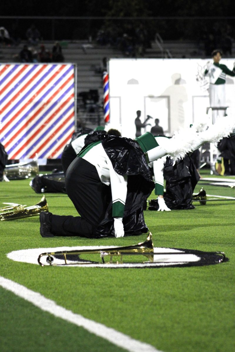 Trombone player bends over on the field.