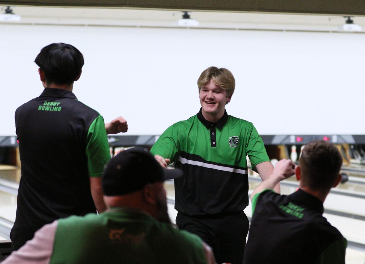 Junior Cash Carns celebrates with his teammates after rolling a strike in the first frame.