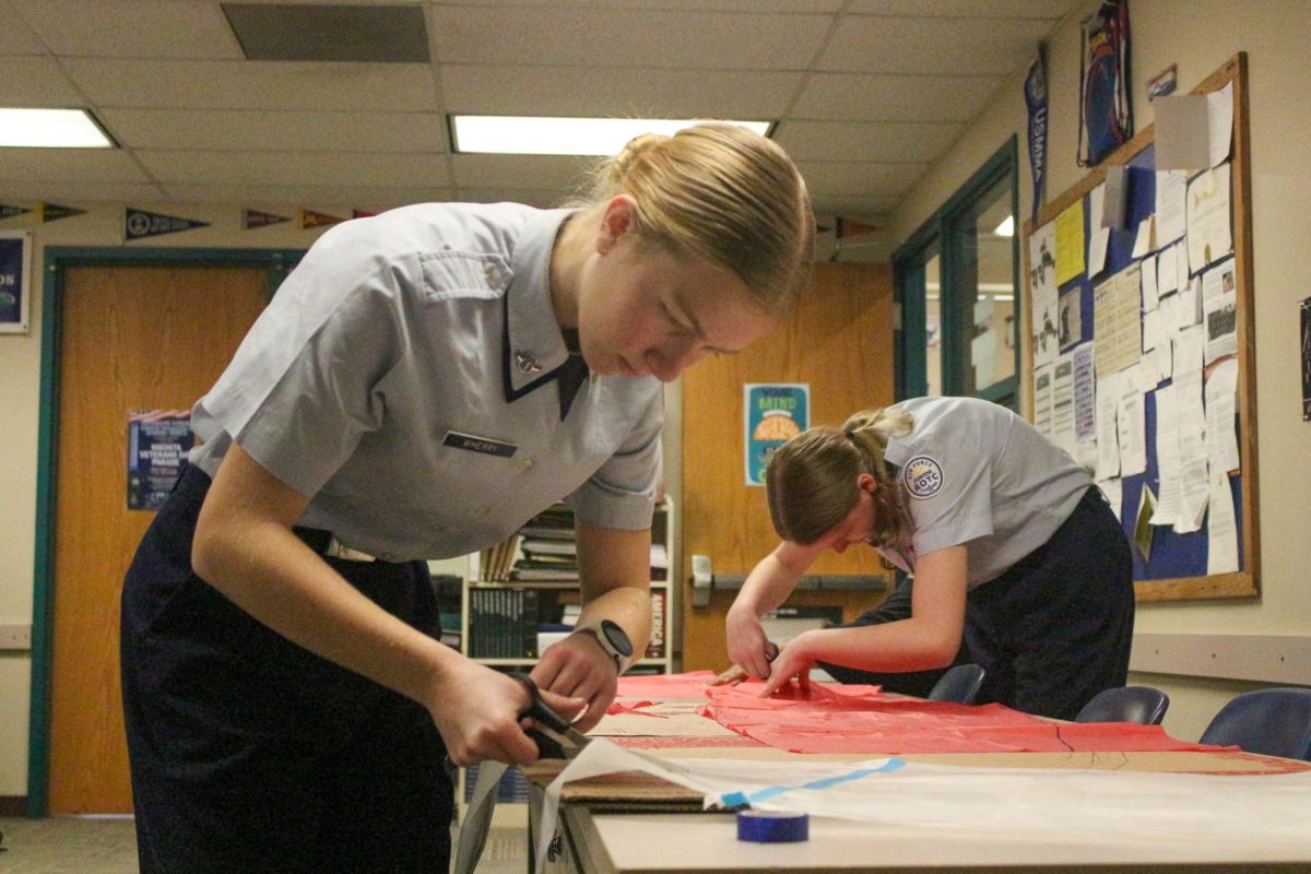 Student cuts tissue paper to make hot air balloon.