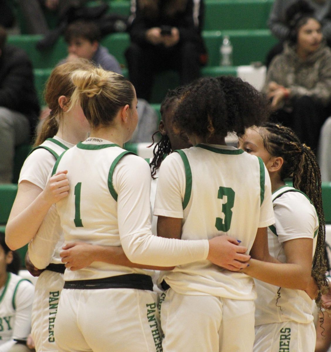 Girls team stands in a huddle before going out onto the court.