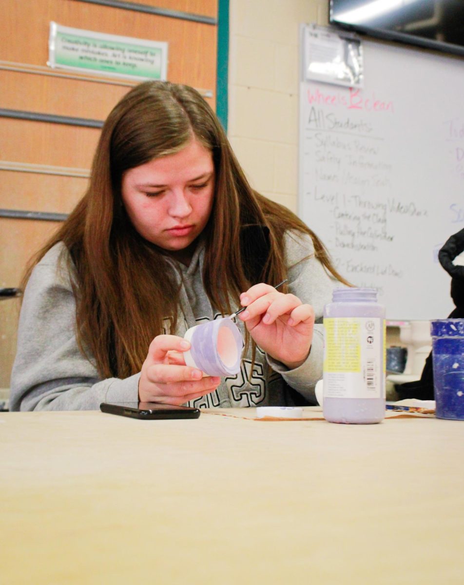 A student uses glaze to paint her project.