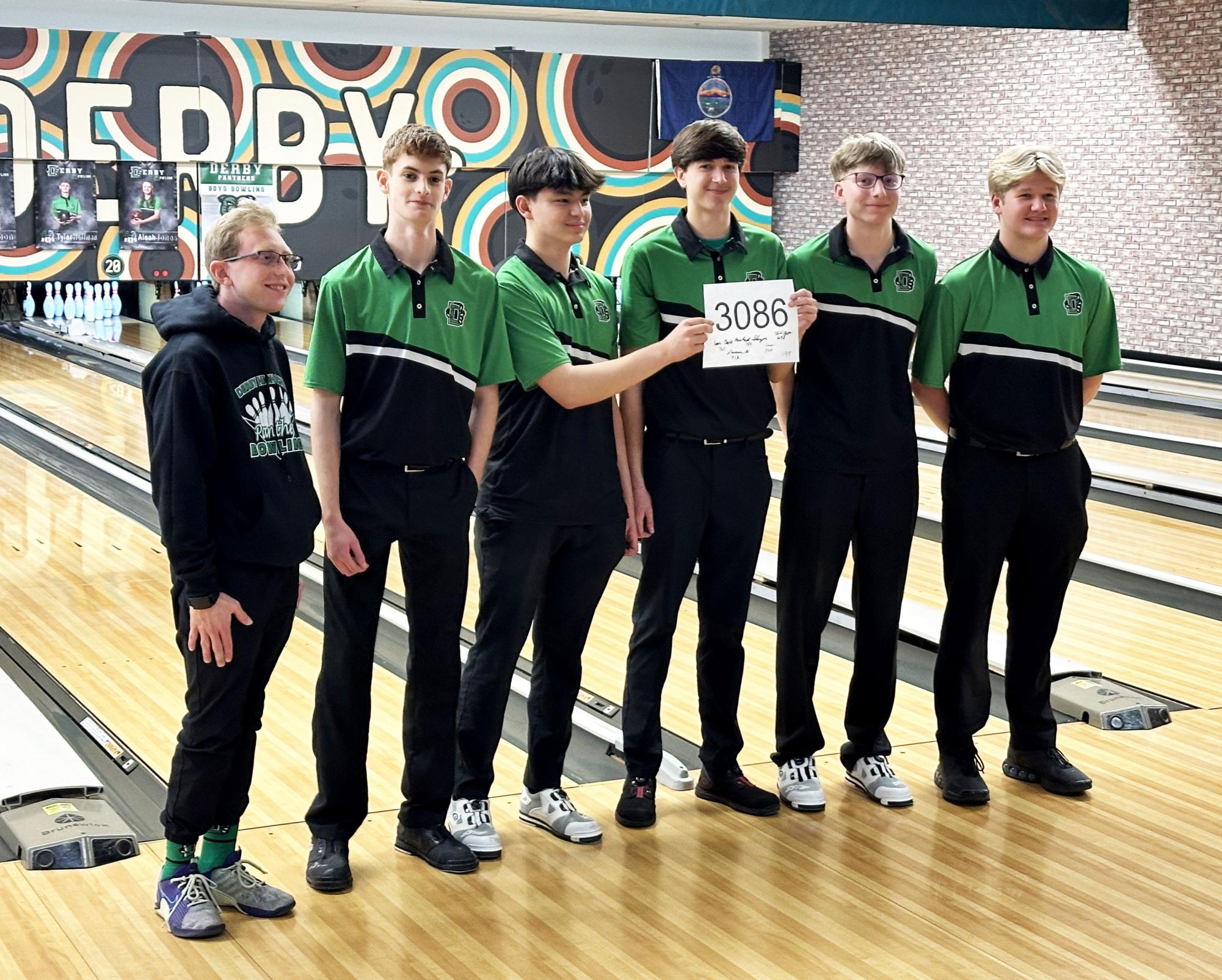 The varsity bowling team poses with a sign commemorating their new state record.