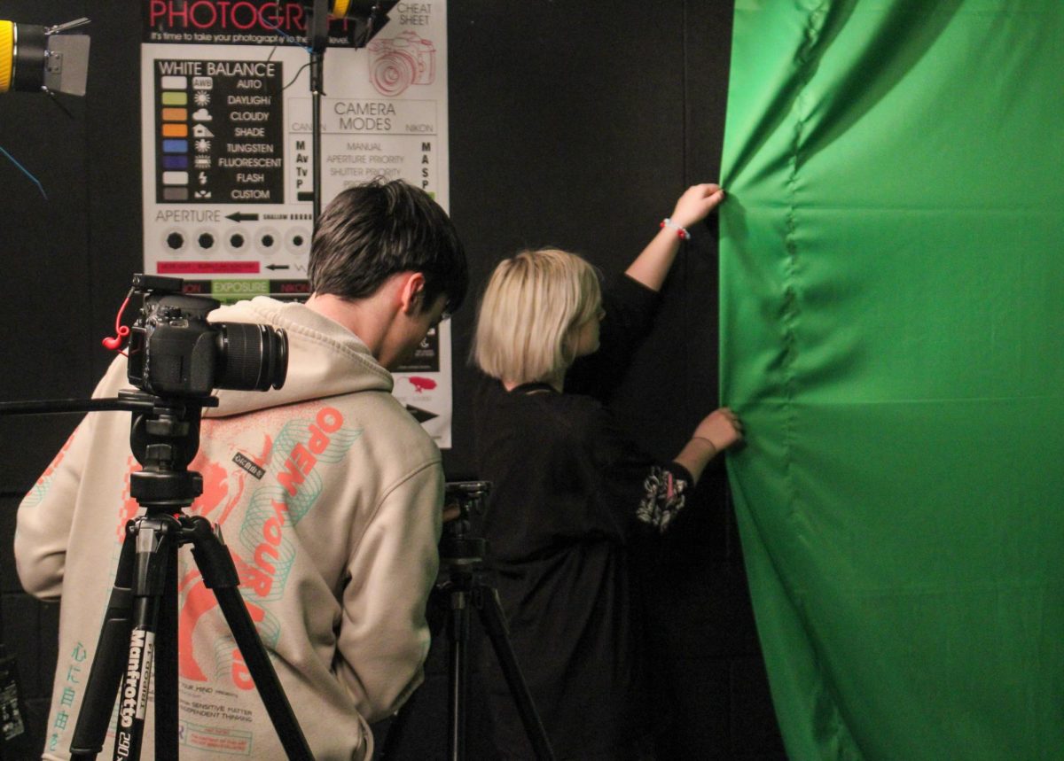 Two DTV students adjust the green screen before recording.