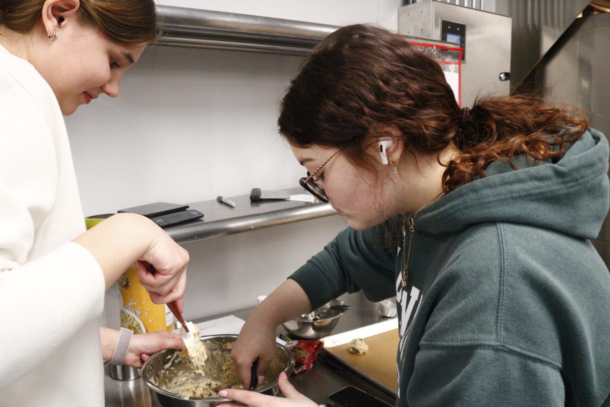 Student scoops batter out of bowl.