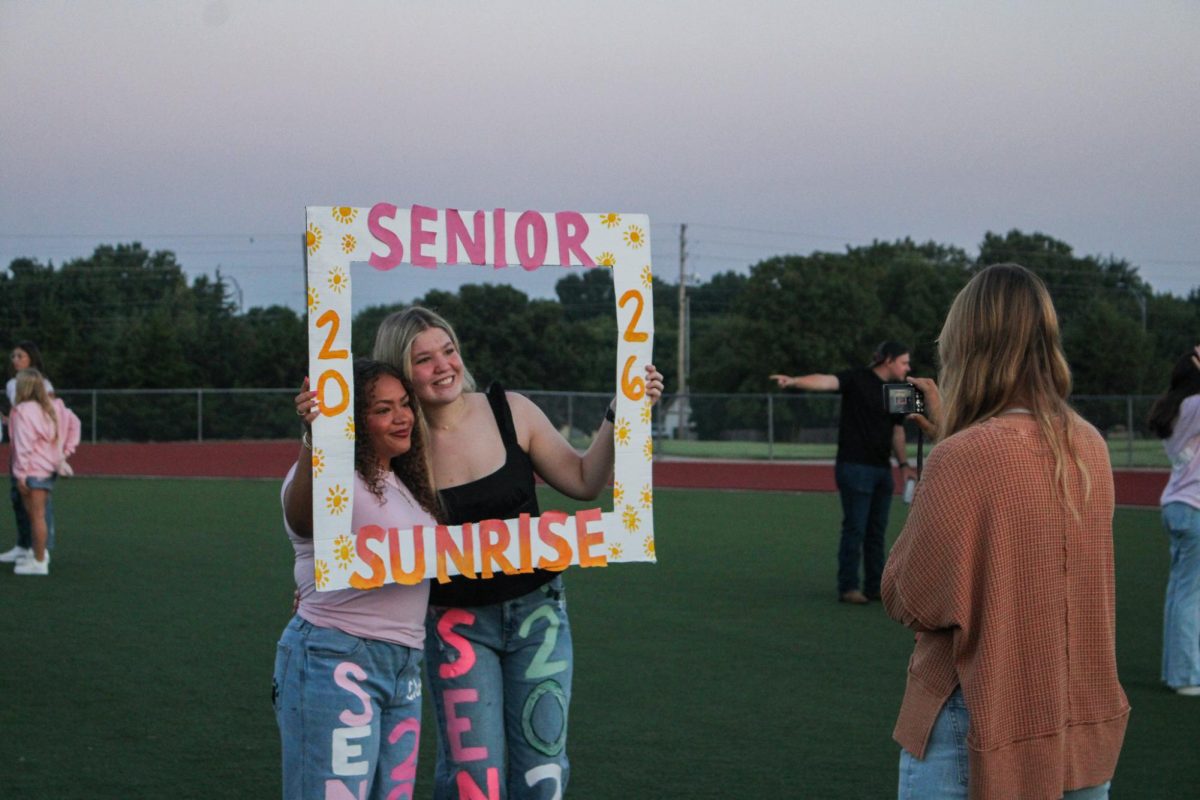 Seniors take a picture with senior sunrise sign. 