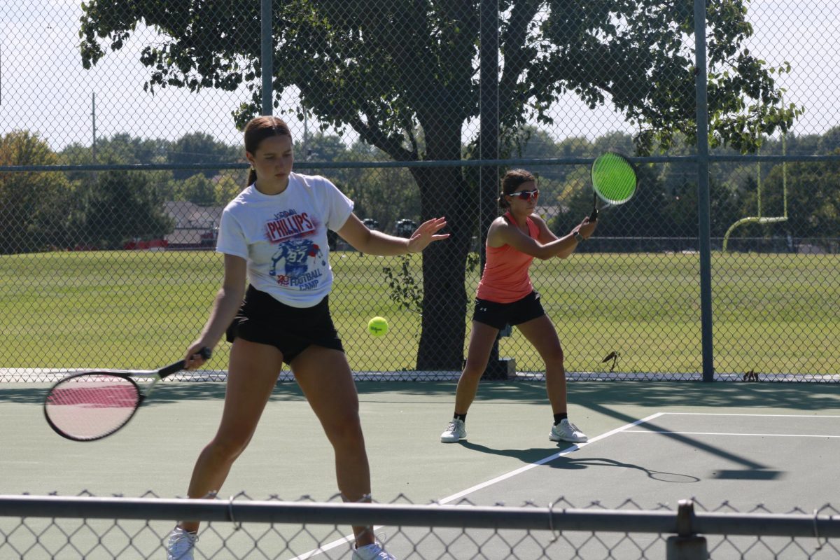 Girls tennis players practice serving and returning. 