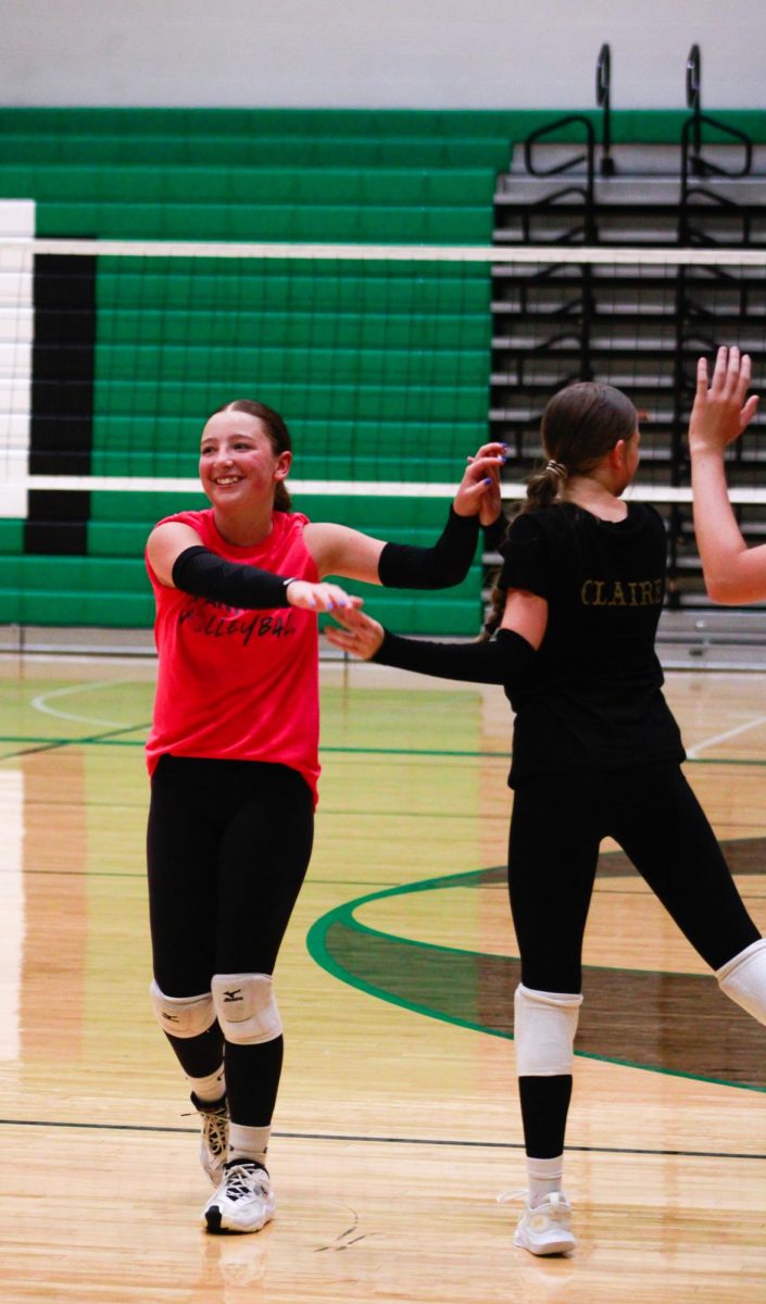 Freshman volleyball player high fives teammate.