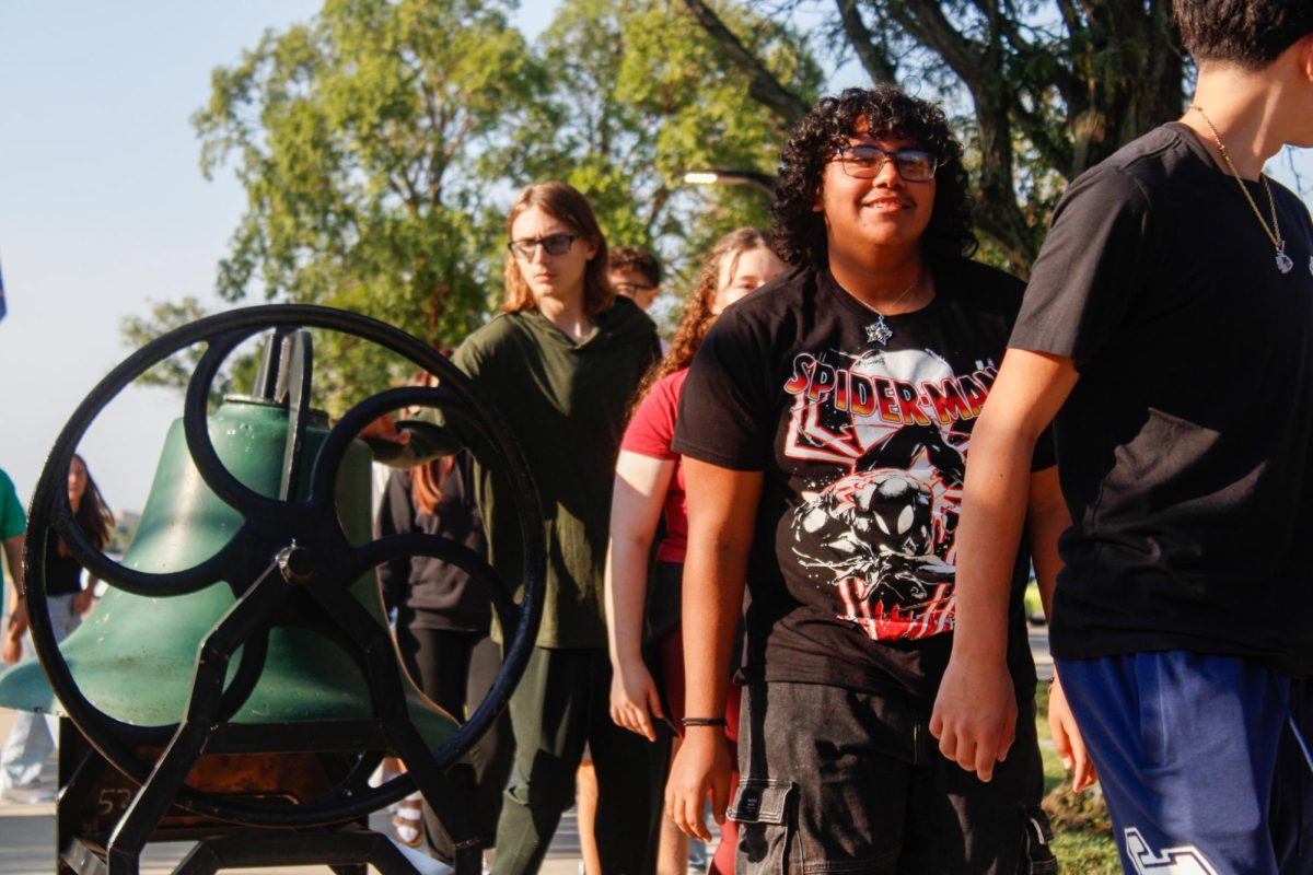 Student walks back into the school after touching the bell. 