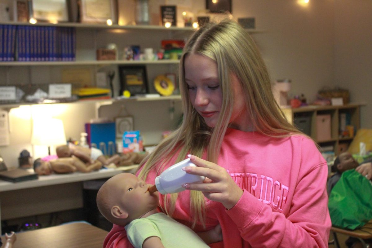 Student feeds baby doll.