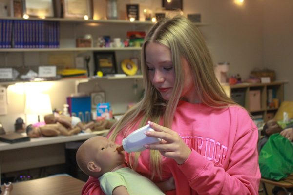 Student feeds baby doll.