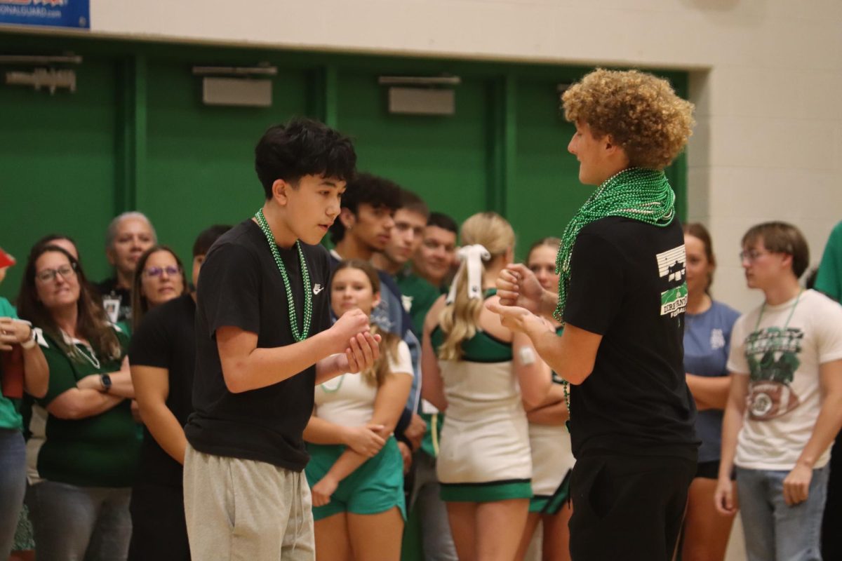 Two students dueling in a game of rock, paper scissors for who will win the beads. 
