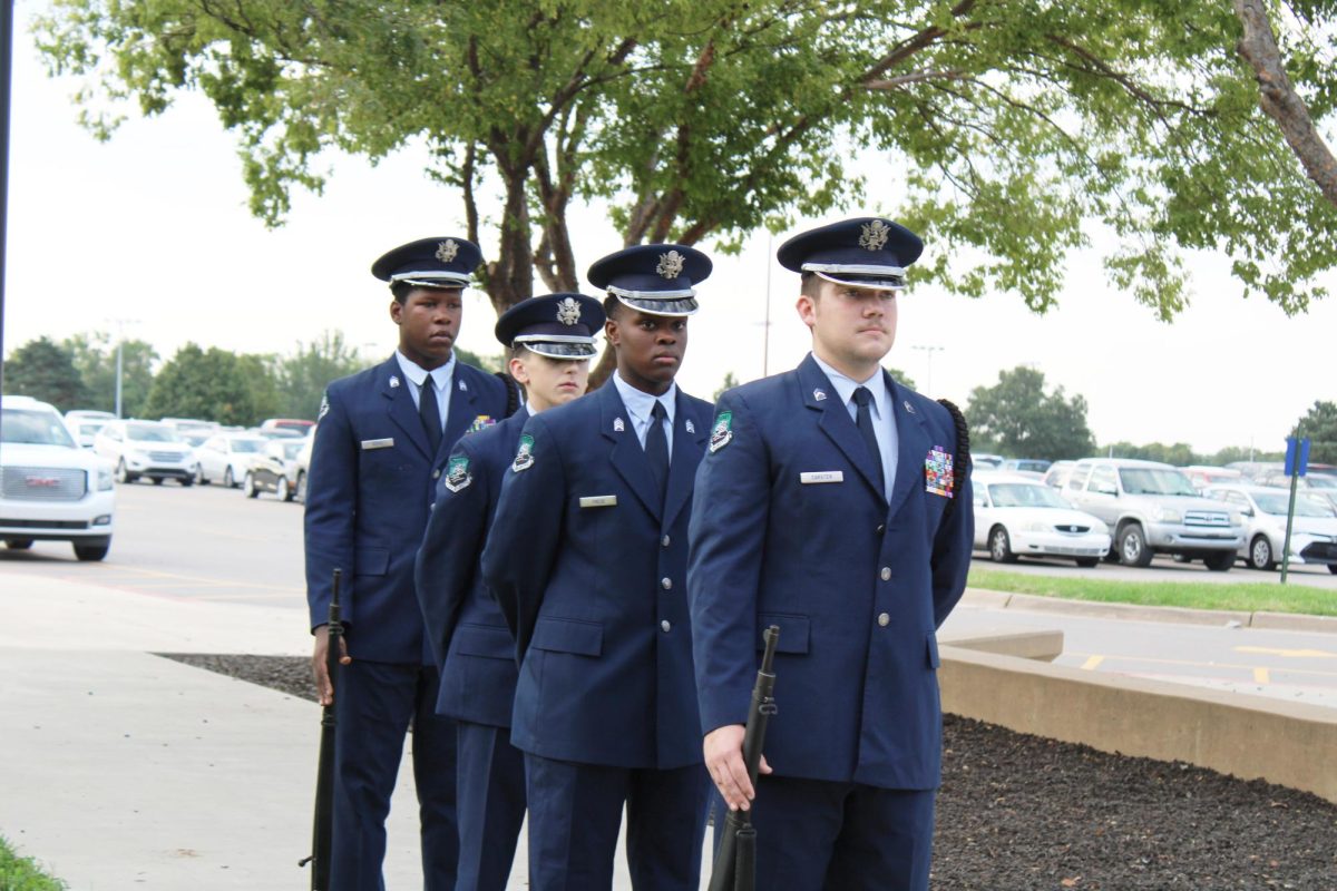 Members of AFJROTC walk in line formation towards the flag pole.