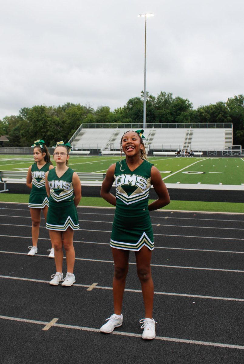 three cheerleaders looking up at crowd