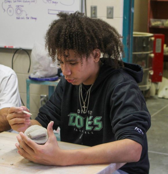 Student works on carving a design into the clay project.