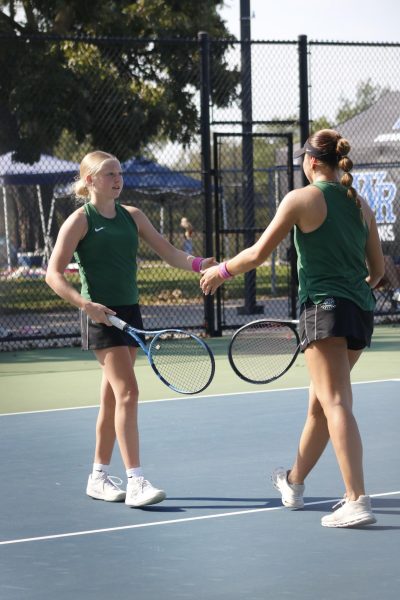 Players walk up to each other to shake hands and tap their rackets. 