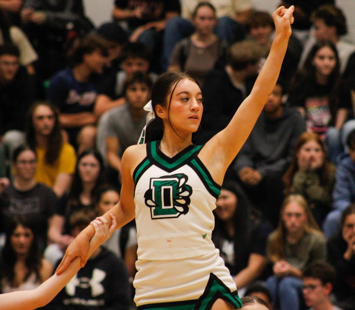 A cheerleader stands up and cheers. 