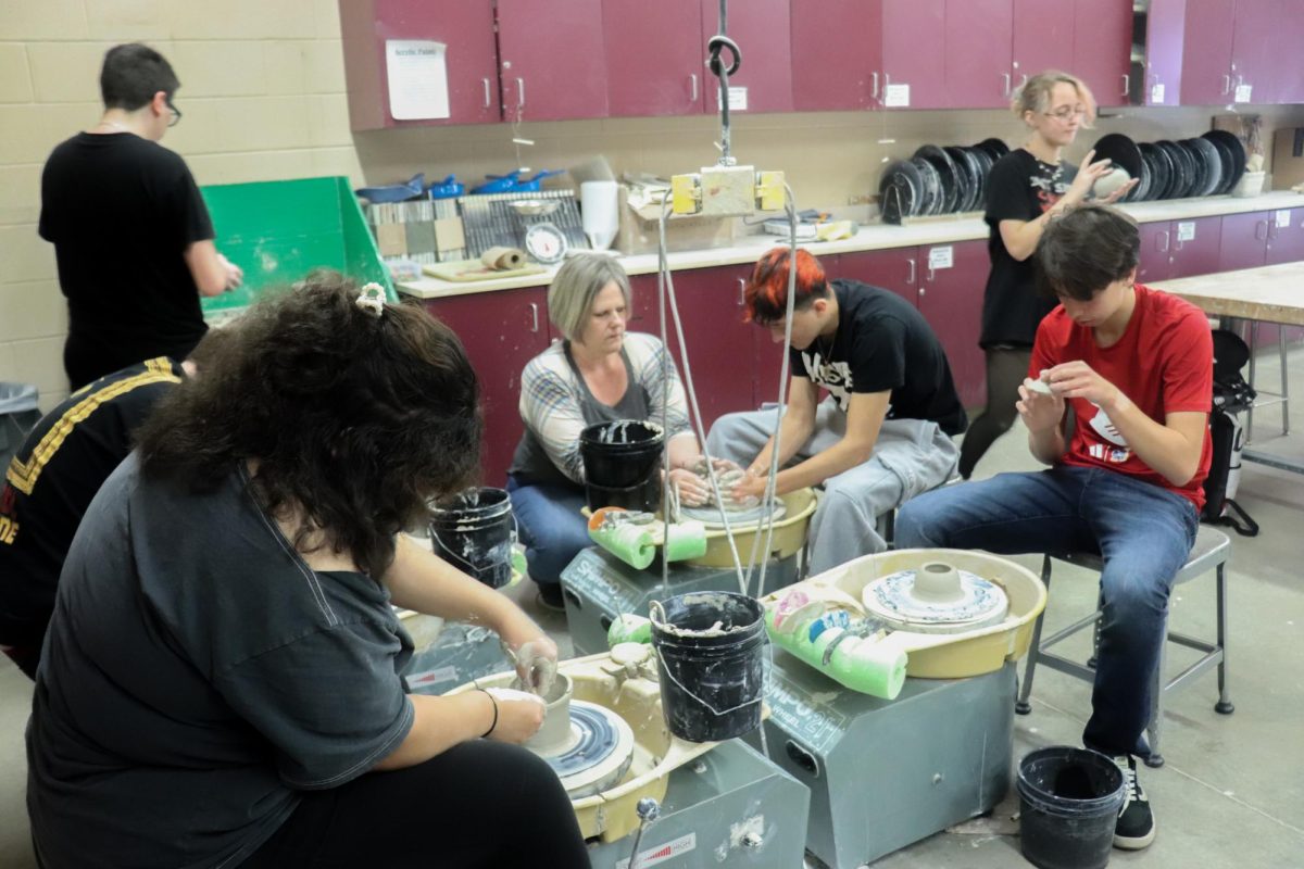 Teacher and students use pottery wheel.