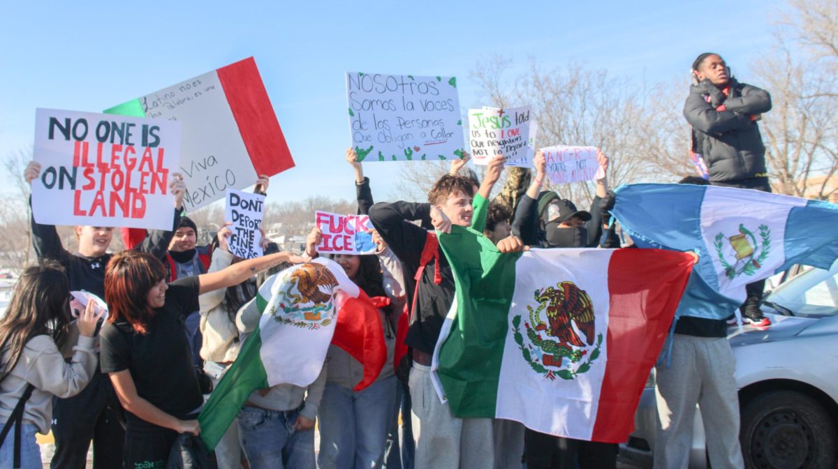 Group of students hold flags and signs in protest.
